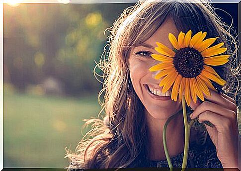 Woman with a sunflower smiling happily