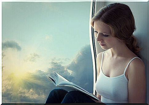 Girl reading a book next to a window