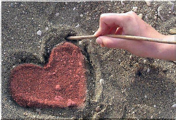 Hand drawing a heart in the sand symbolizing the art of doing good