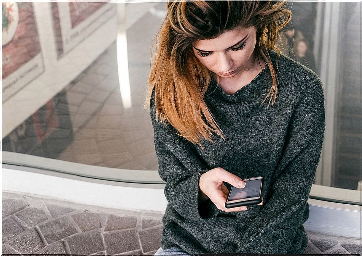 Woman looking at mobile leaning wall