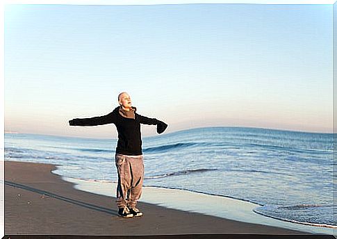 Woman with cancer on the beach with open arms