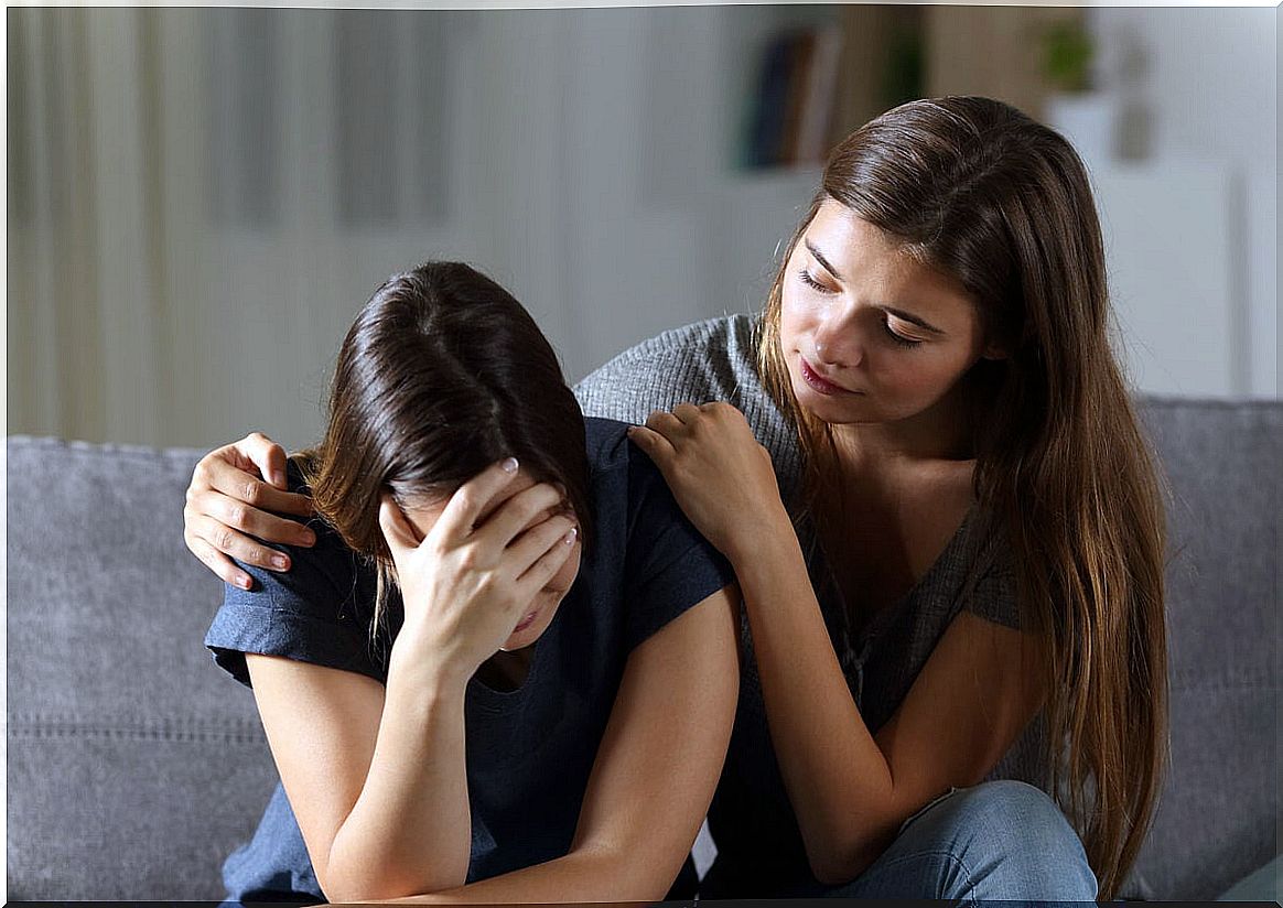 Girl sad by grief with her friend comforting her